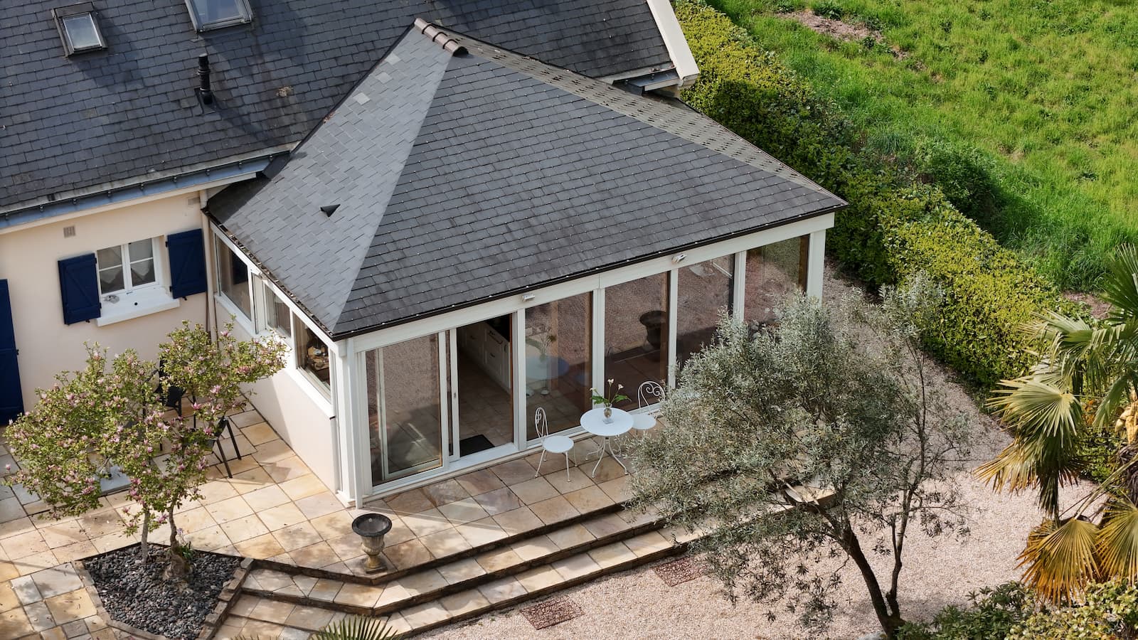 Vue aérienne en hauteur d'une propriété avec terrasse, véranda et allée gravillonnée